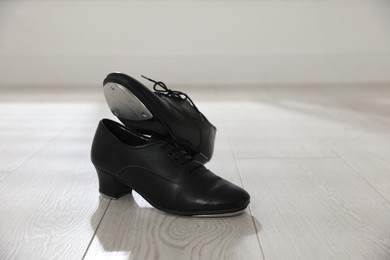 Photo of Pair of shoes for tap dance on floor indoors, space for text