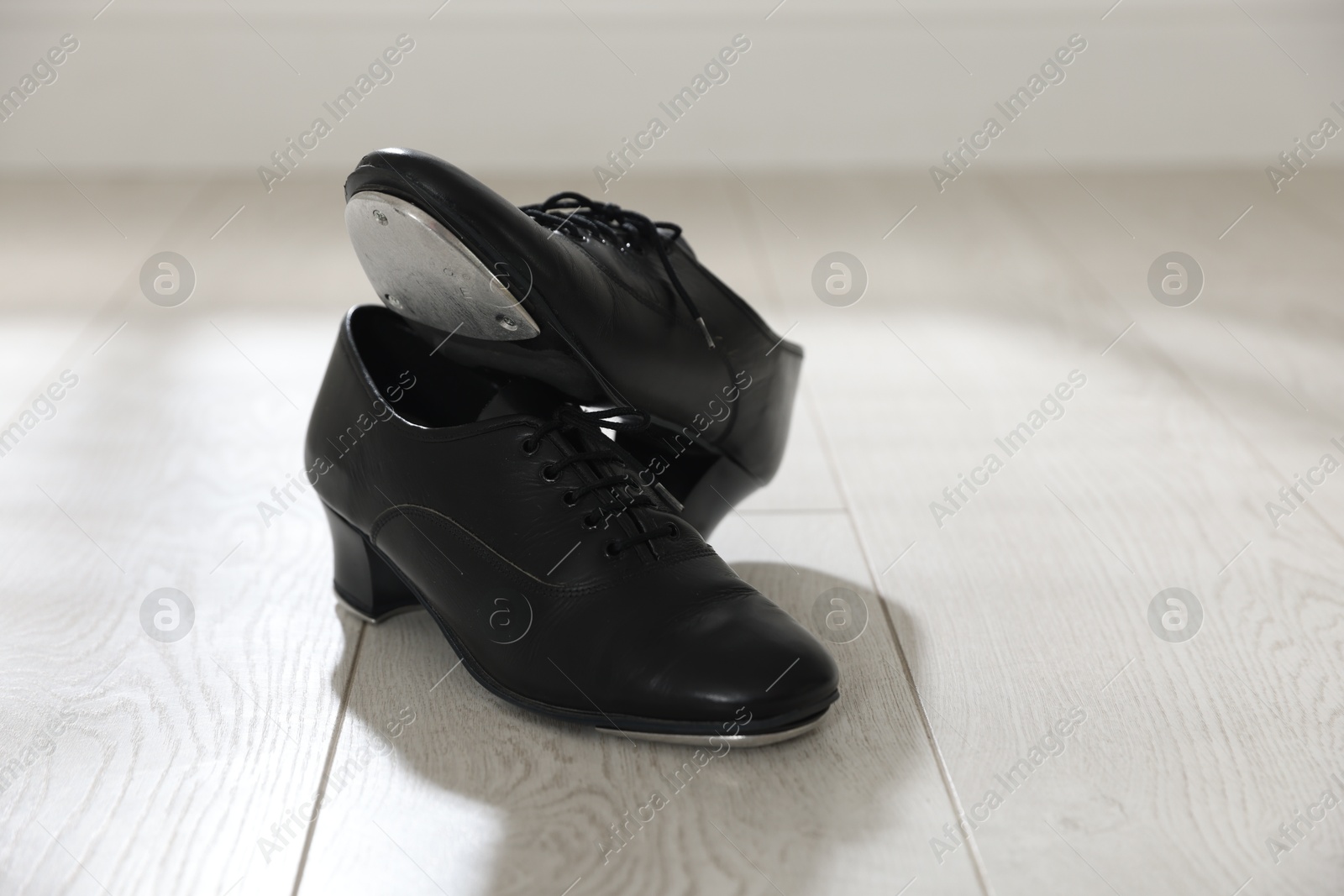 Photo of Pair of shoes for tap dance on floor indoors, closeup. Space for text