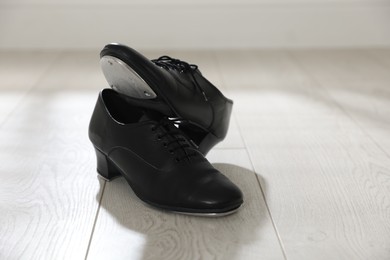 Photo of Pair of shoes for tap dance on floor indoors, closeup. Space for text