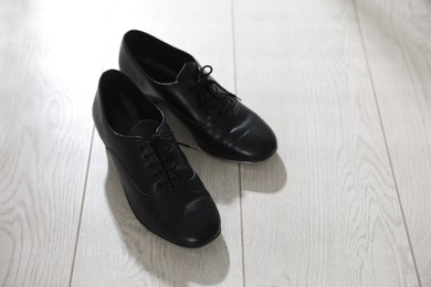 Photo of Pair of shoes for tap dance on floor indoors, above view. Space for text