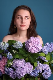 Photo of Portrait of beautiful woman with hortensia flowers on blue background