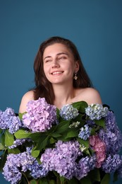 Photo of Smiling woman with hortensia flowers on blue background