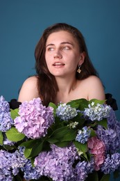 Photo of Portrait of beautiful woman with hortensia flowers on blue background