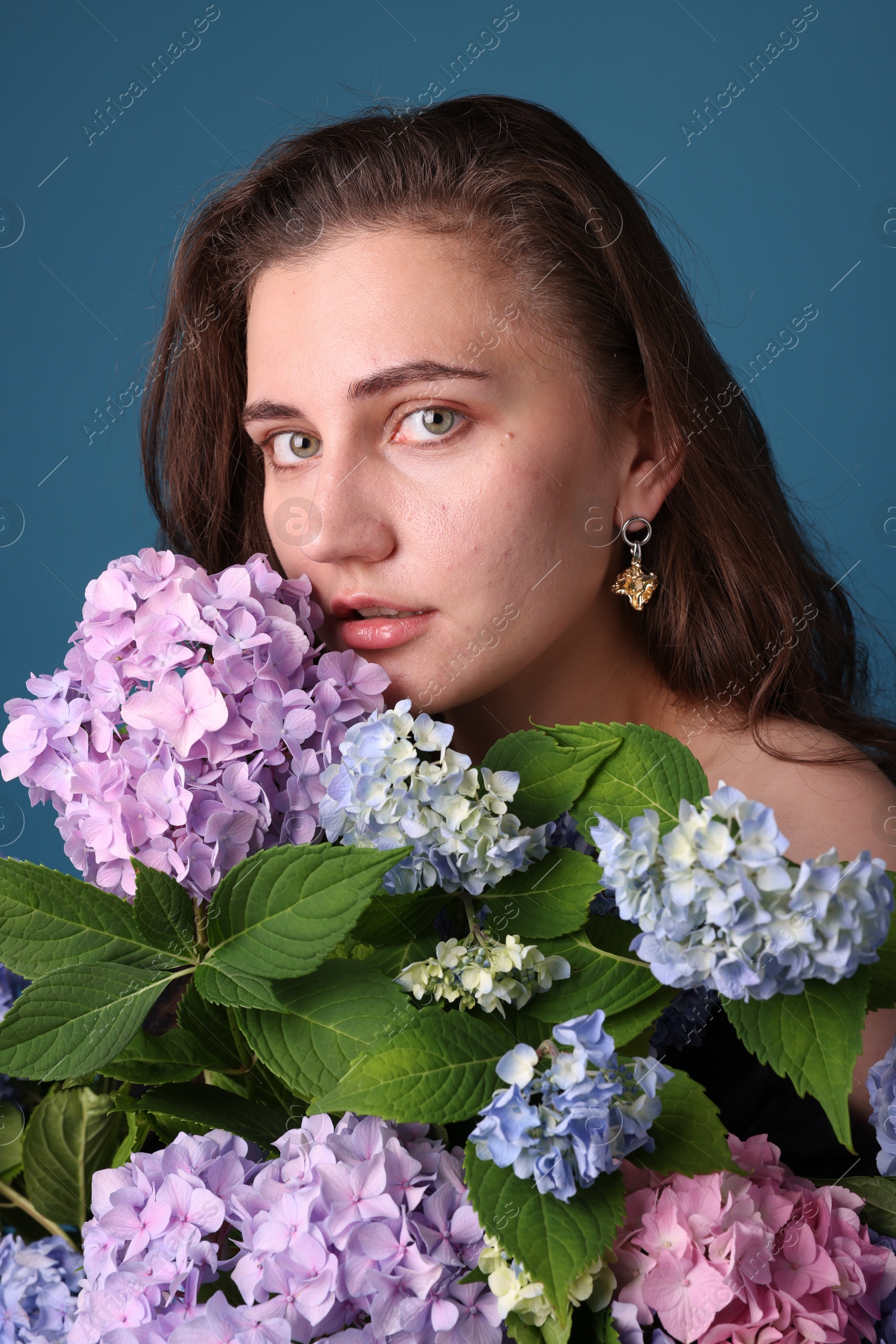Photo of Portrait of beautiful woman with hortensia flowers on blue background