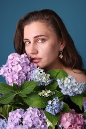 Photo of Portrait of beautiful woman with hortensia flowers on blue background