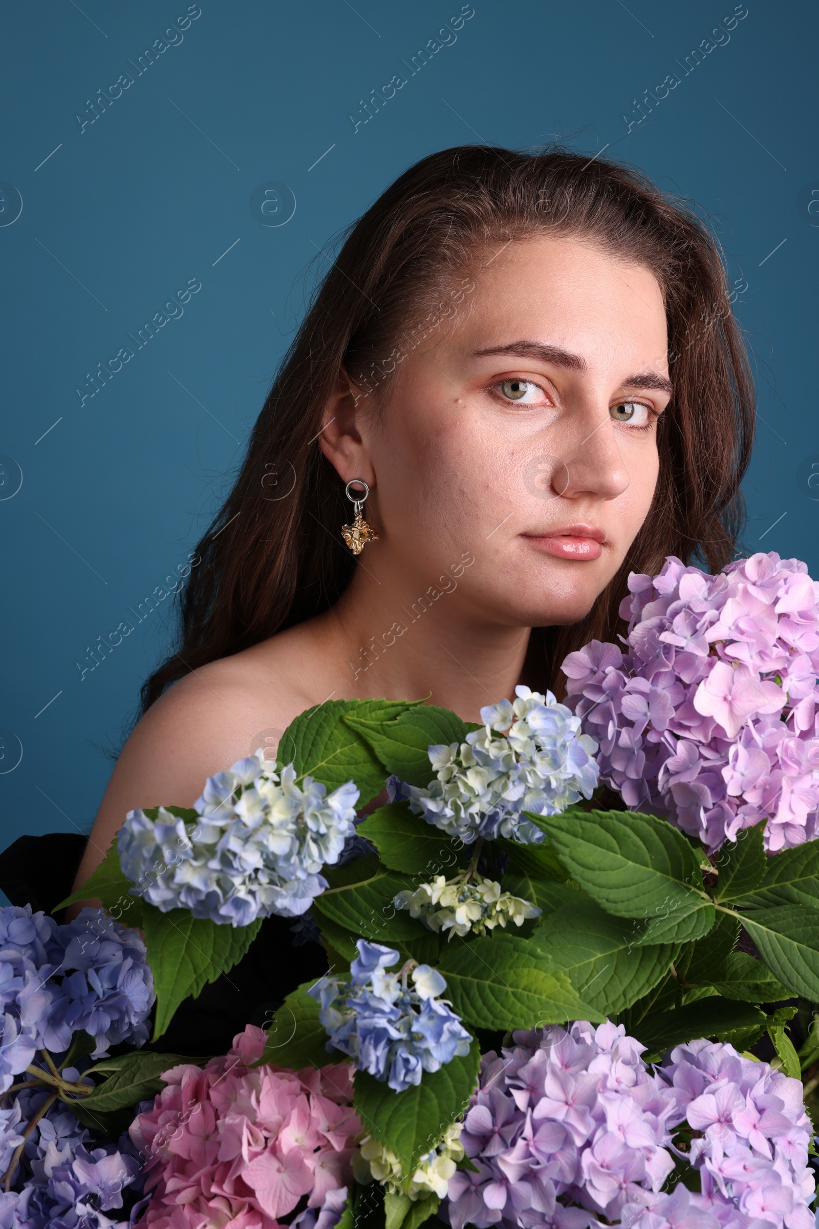 Photo of Portrait of beautiful woman with hortensia flowers on blue background