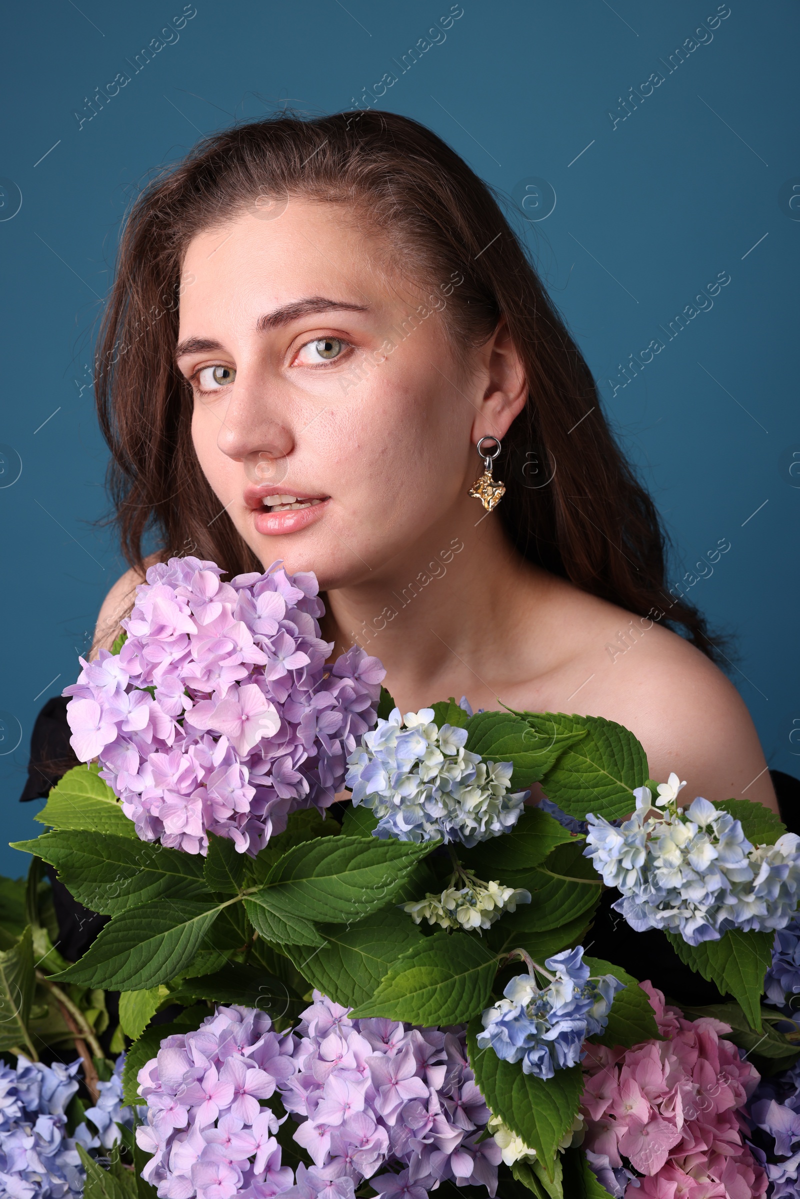 Photo of Portrait of beautiful woman with hortensia flowers on blue background