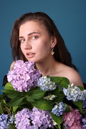 Photo of Portrait of beautiful woman with hortensia flowers on blue background