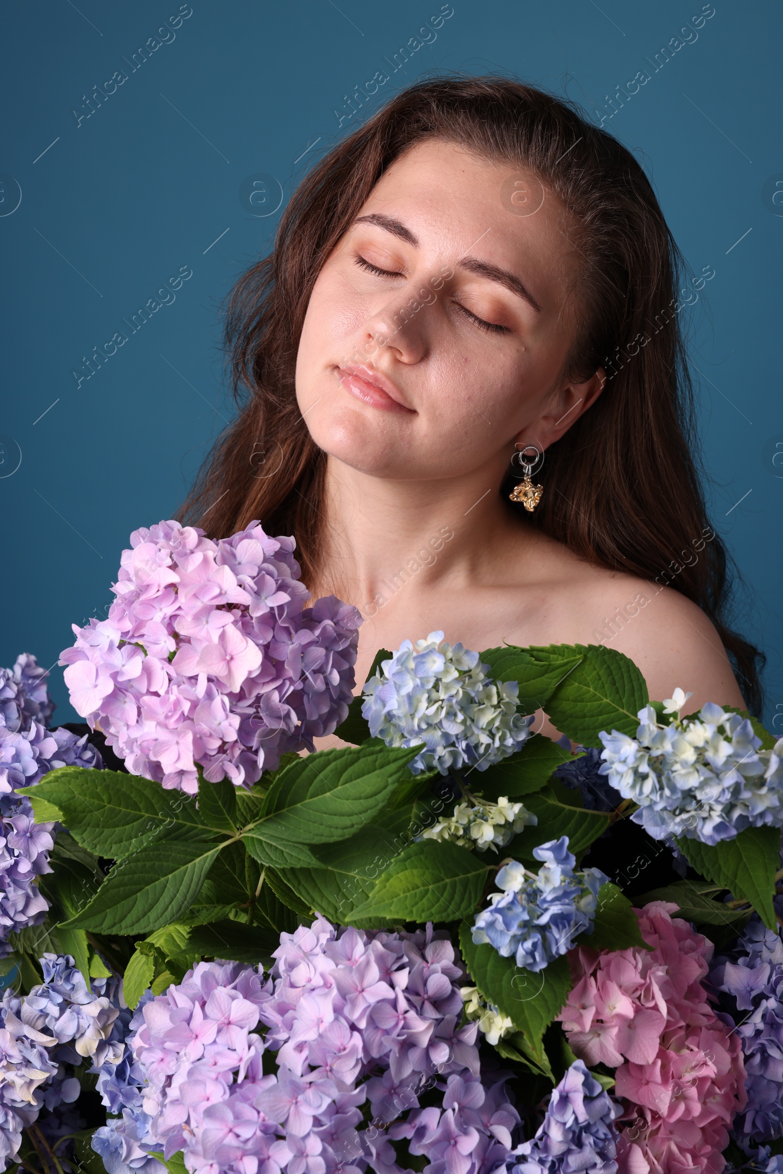 Photo of Beautiful woman with hortensia flowers on blue background