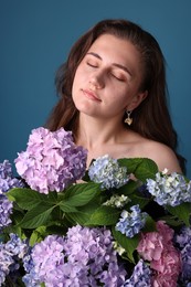 Photo of Beautiful woman with hortensia flowers on blue background