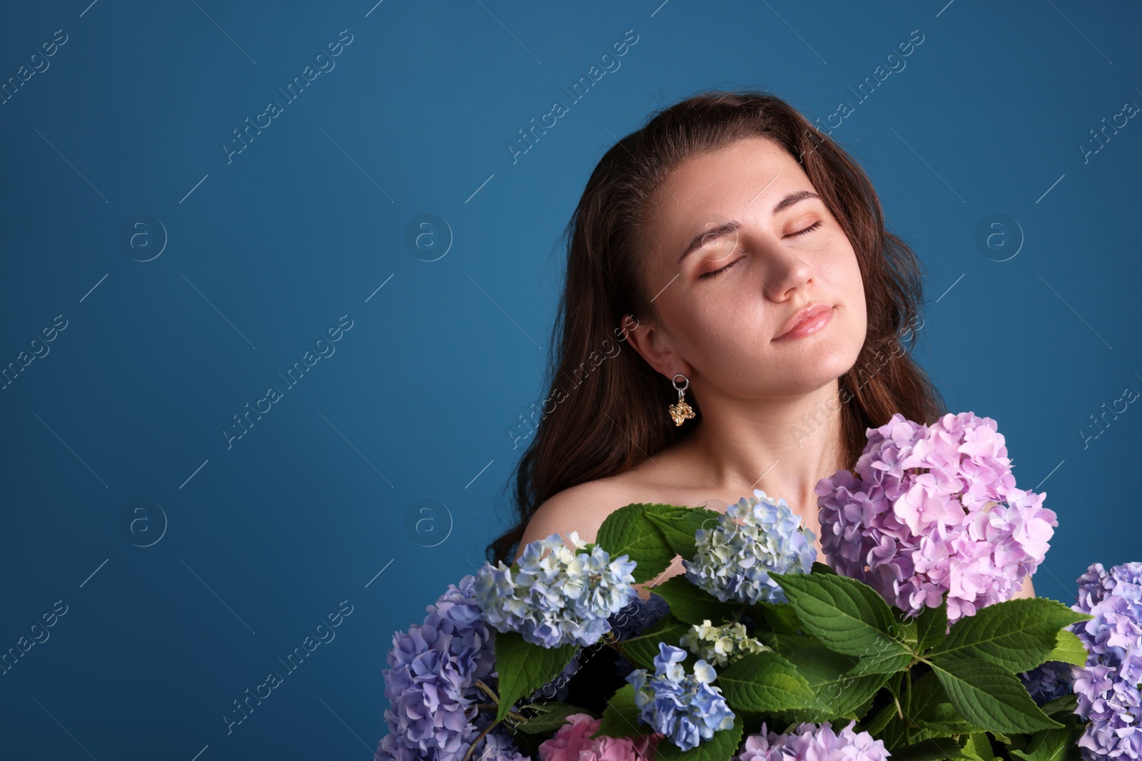 Photo of Beautiful woman with hortensia flowers on blue background. Space for text