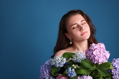 Photo of Beautiful woman with hortensia flowers on blue background. Space for text