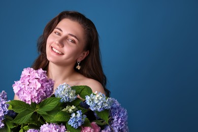 Photo of Portrait of smiling woman with hortensia flowers on blue background. Space for text