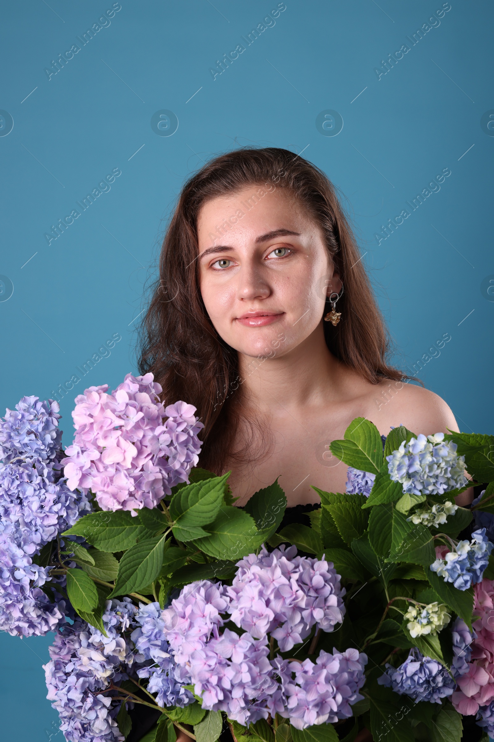Photo of Portrait of beautiful woman with hortensia flowers on blue background