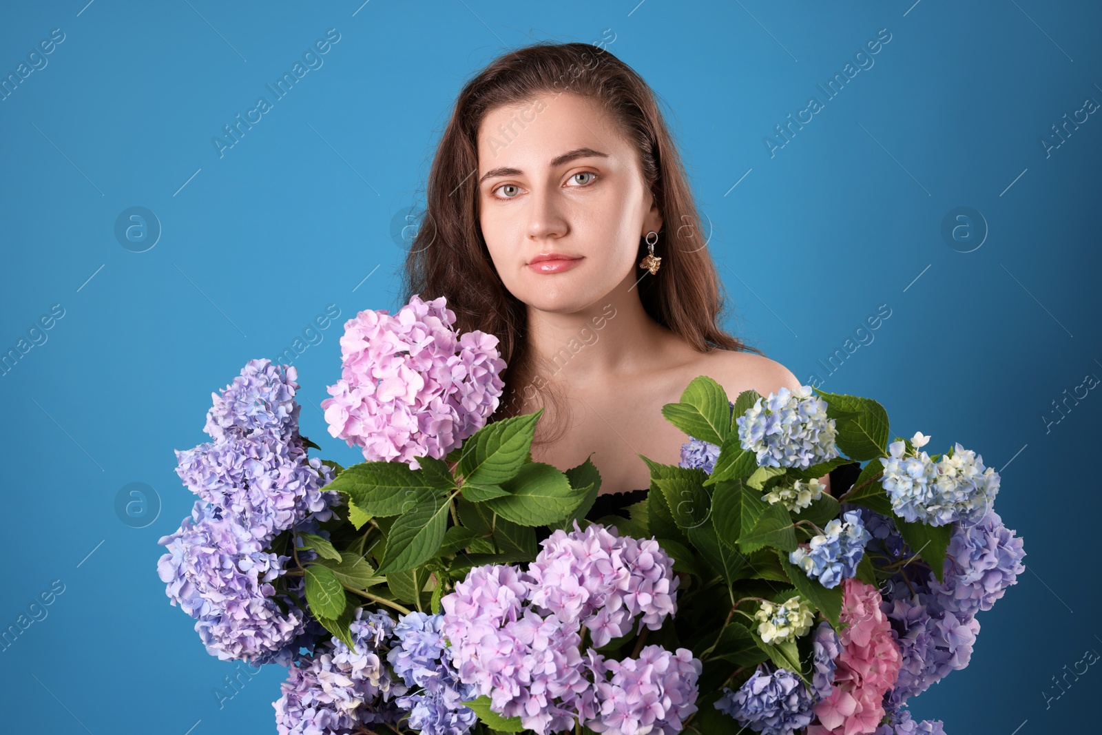 Photo of Portrait of beautiful woman with hortensia flowers on blue background