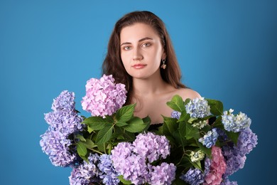 Photo of Portrait of beautiful woman with hortensia flowers on blue background