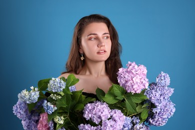 Photo of Portrait of beautiful woman with hortensia flowers on blue background