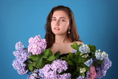 Photo of Portrait of beautiful woman with hortensia flowers on blue background