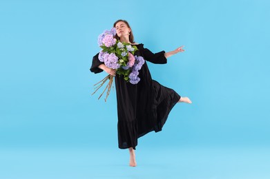 Photo of Beautiful woman in dress with hortensia flowers on light blue background