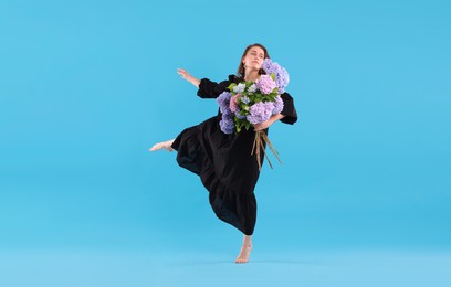 Photo of Beautiful woman in dress with hortensia flowers on light blue background
