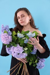 Photo of Portrait of beautiful woman with bouquet of hortensia flowers on light blue background