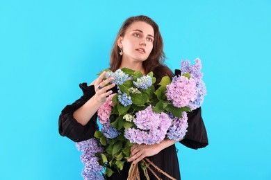 Photo of Beautiful woman with bouquet of hortensia flowers on light blue background