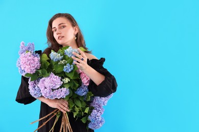 Photo of Portrait of beautiful woman with bouquet of hortensia flowers on light blue background. Space for text