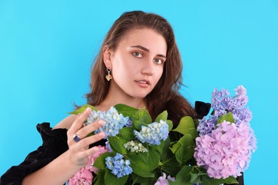 Photo of Portrait of beautiful woman with hortensia flowers on light blue background