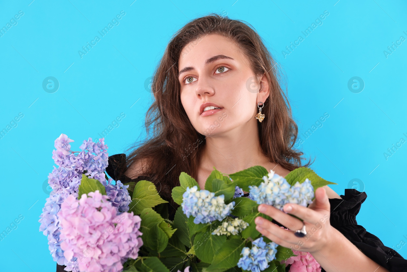 Portrait of beautiful woman with hortensia flowers on light blue background Photo of Portrait of beautiful woman with hortensia flowers on light blue background