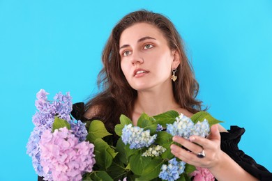 Photo of Portrait of beautiful woman with hortensia flowers on light blue background