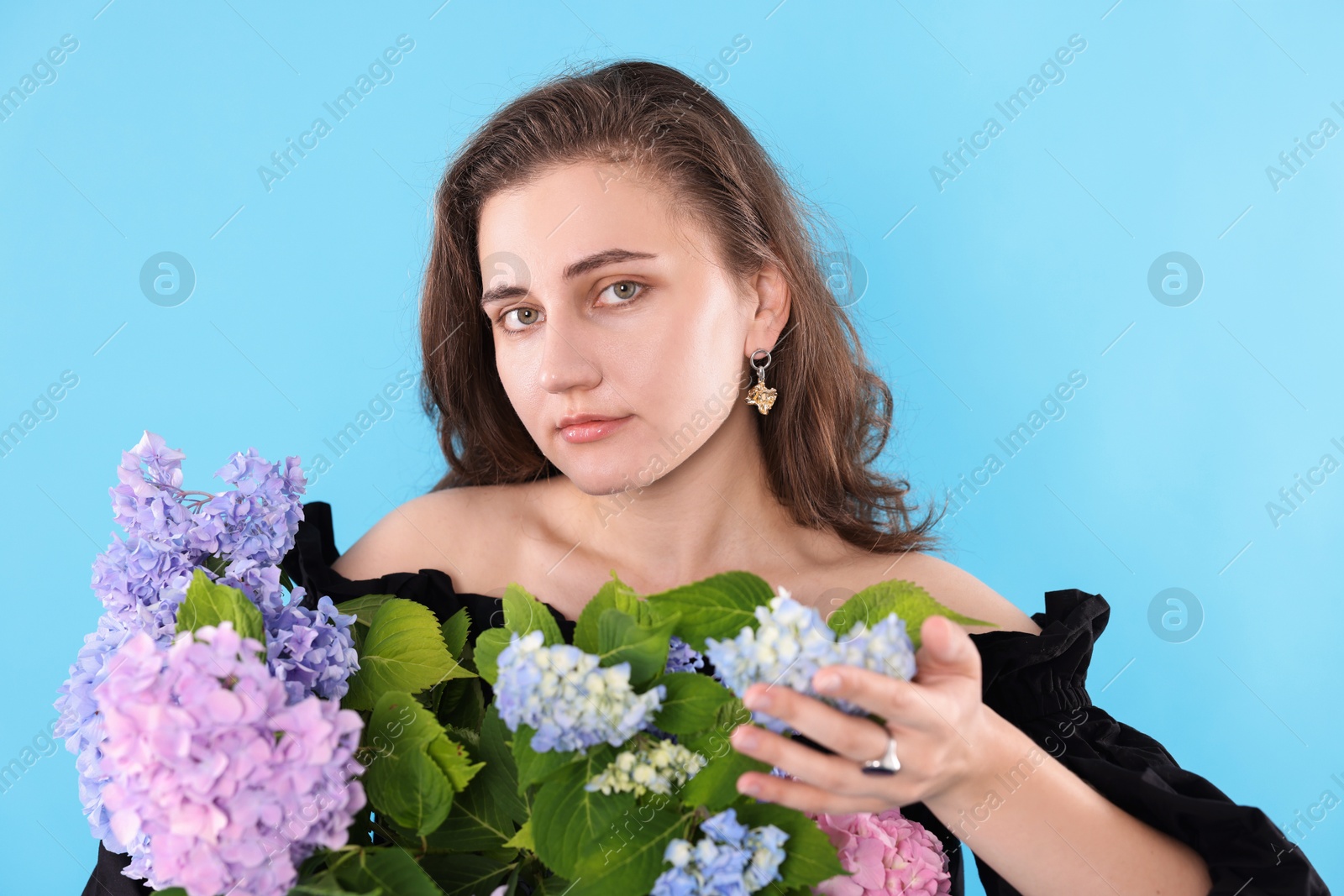 Portrait of beautiful woman with hortensia flowers on light blue background Photo of Portrait of beautiful woman with hortensia flowers on light blue background