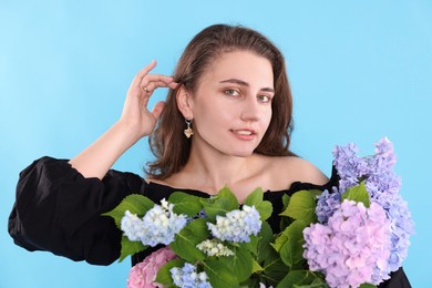 Photo of Portrait of smiling woman with hortensia flowers on light blue background