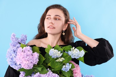 Photo of Portrait of smiling woman with hortensia flowers on light blue background