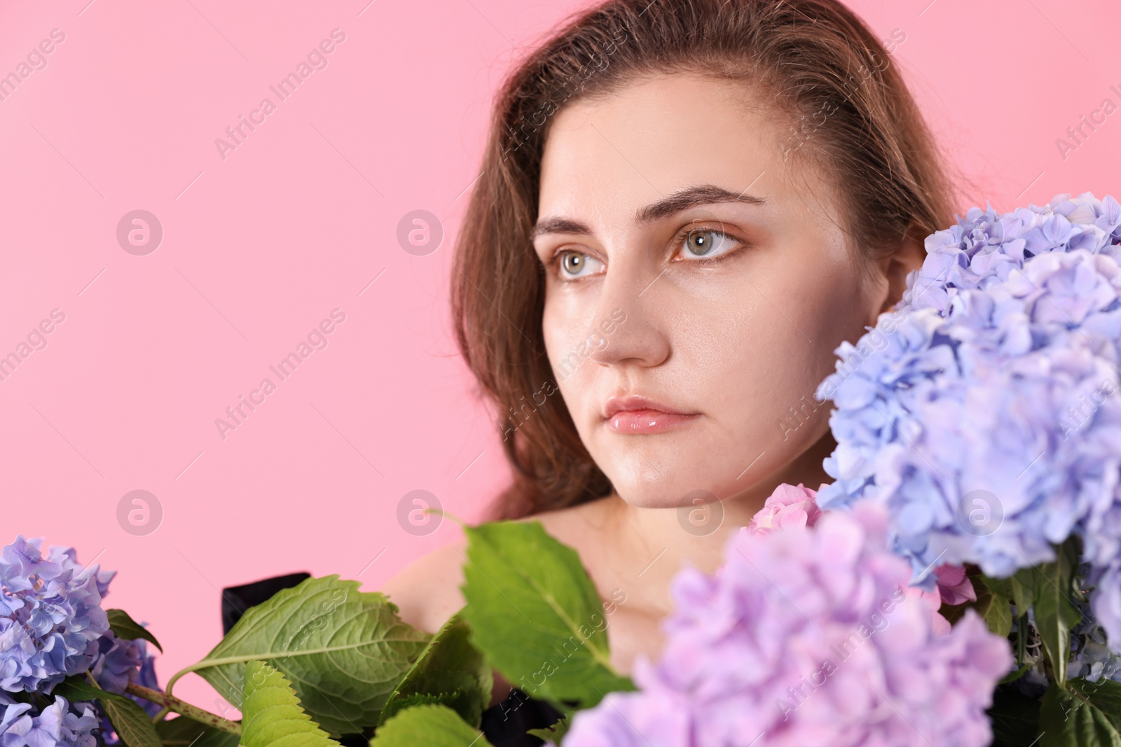 Beautiful woman with hortensia flowers on pink background Photo of Beautiful woman with hortensia flowers on pink background