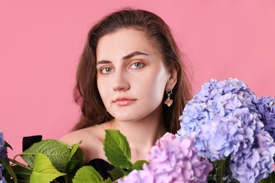 Photo of Portrait of beautiful woman with hortensia flowers on pink background
