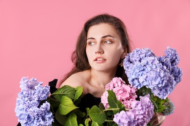 Photo of Beautiful woman with hortensia flowers on pink background