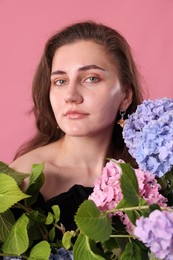 Photo of Portrait of beautiful woman with hortensia flowers on pink background