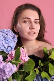 Photo of Portrait of beautiful woman with hortensia flowers on pink background