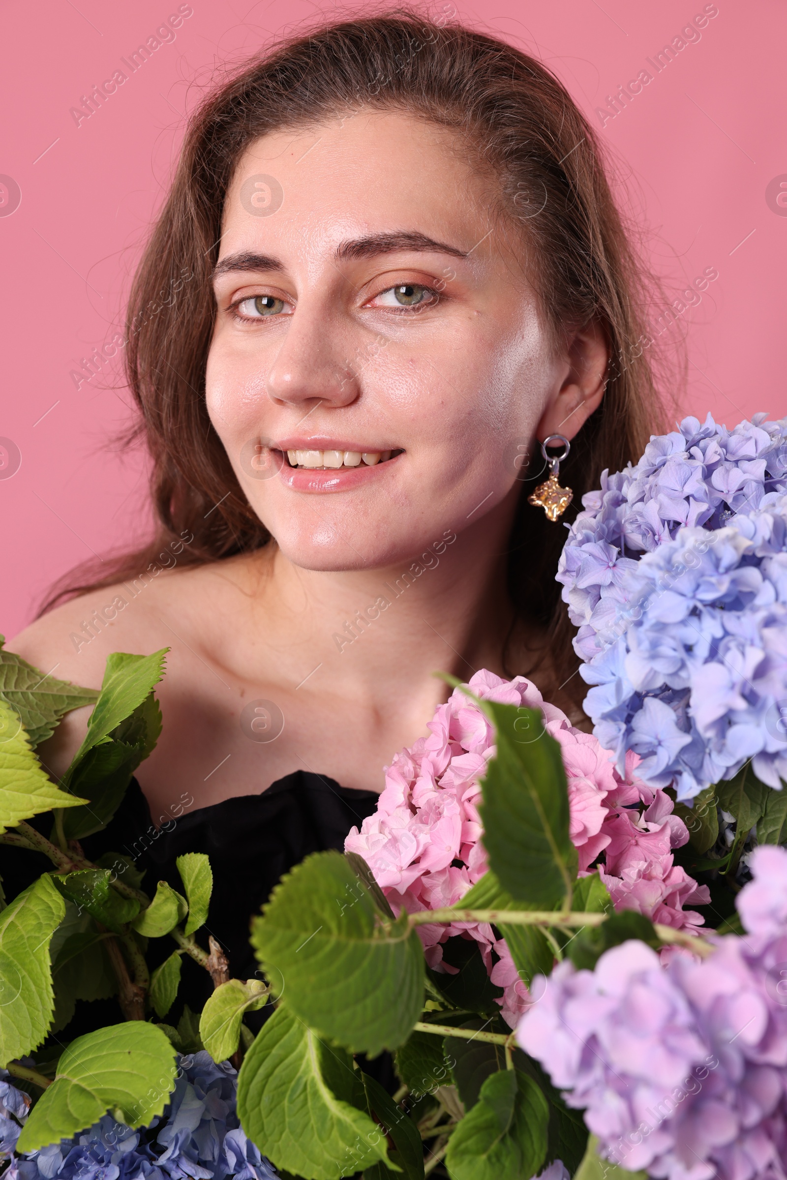Portrait of smiling woman with hortensia flowers on pink background Photo of Portrait of smiling woman with hortensia flowers on pink background