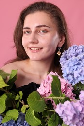 Photo of Portrait of smiling woman with hortensia flowers on pink background