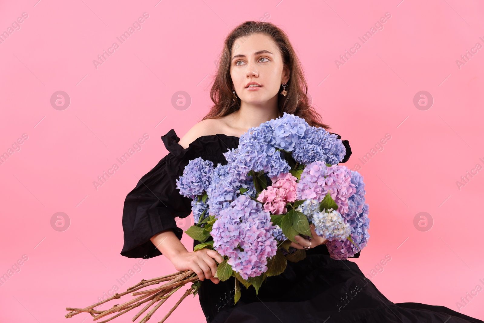 Portrait of beautiful woman in dress with bouquet of hortensia flowers on pink background Photo of Portrait of beautiful woman in dress with bouquet of hortensia flowers on pink background