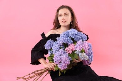 Photo of Portrait of beautiful woman in dress with bouquet of hortensia flowers on pink background
