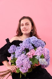 Photo of Portrait of smiling woman with hortensia flowers on pink background