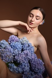 Photo of Beautiful young woman with hortensia flowers on brown background
