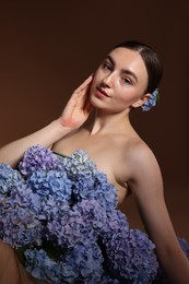 Photo of Beautiful young woman with hortensia flowers on brown background