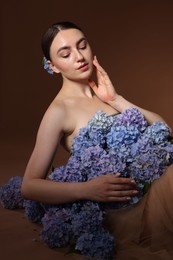 Photo of Beautiful young woman with hortensia flowers on brown background