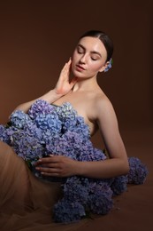 Photo of Beautiful young woman with hortensia flowers on brown background