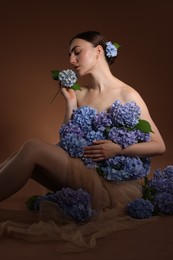 Photo of Beautiful young woman with hortensia flowers on brown background