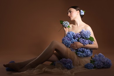 Photo of Beautiful young woman with hortensia flowers on brown background