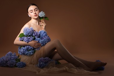 Photo of Beautiful young woman with hortensia flowers on brown background
